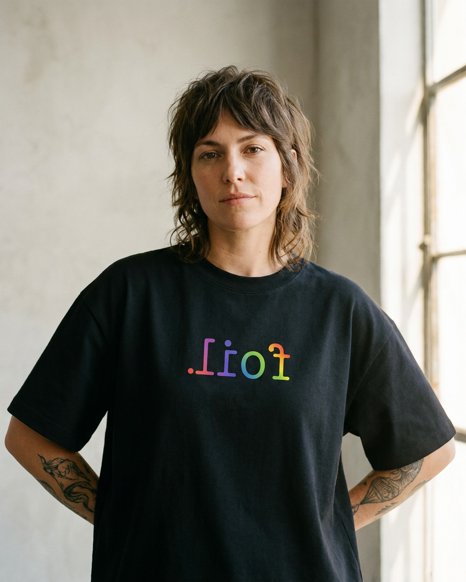 Person wearing a black t-shirt with colorful text in front of a window.