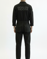 Person wearing a black boiler suit with 'Boiler Room' branding on a white background