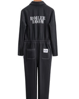 Black Foil Style Boiler Room jumpsuit shown from the back on a wooden hanger, featuring 'BOILER ROOM' printed across the shoulders and a logo patch on the back pocket, against a white background