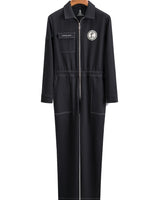 Black Foil Style Boiler Room jumpsuit shown from the front on a wooden hanger, featuring a chest pocket, front zipper, and circular logo patch, against a white background