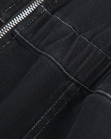 Close-up detail of black fabric with white contrast stitching and a silver zipper.