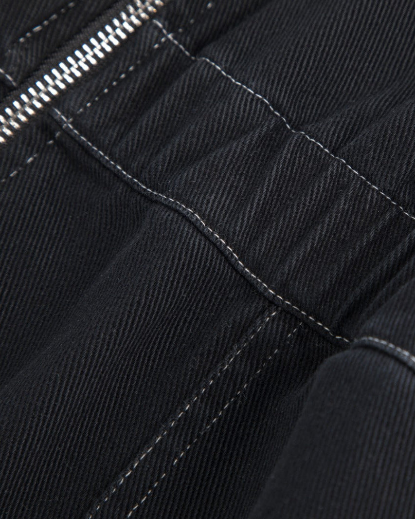 Close-up detail of black fabric with white contrast stitching and a silver zipper.