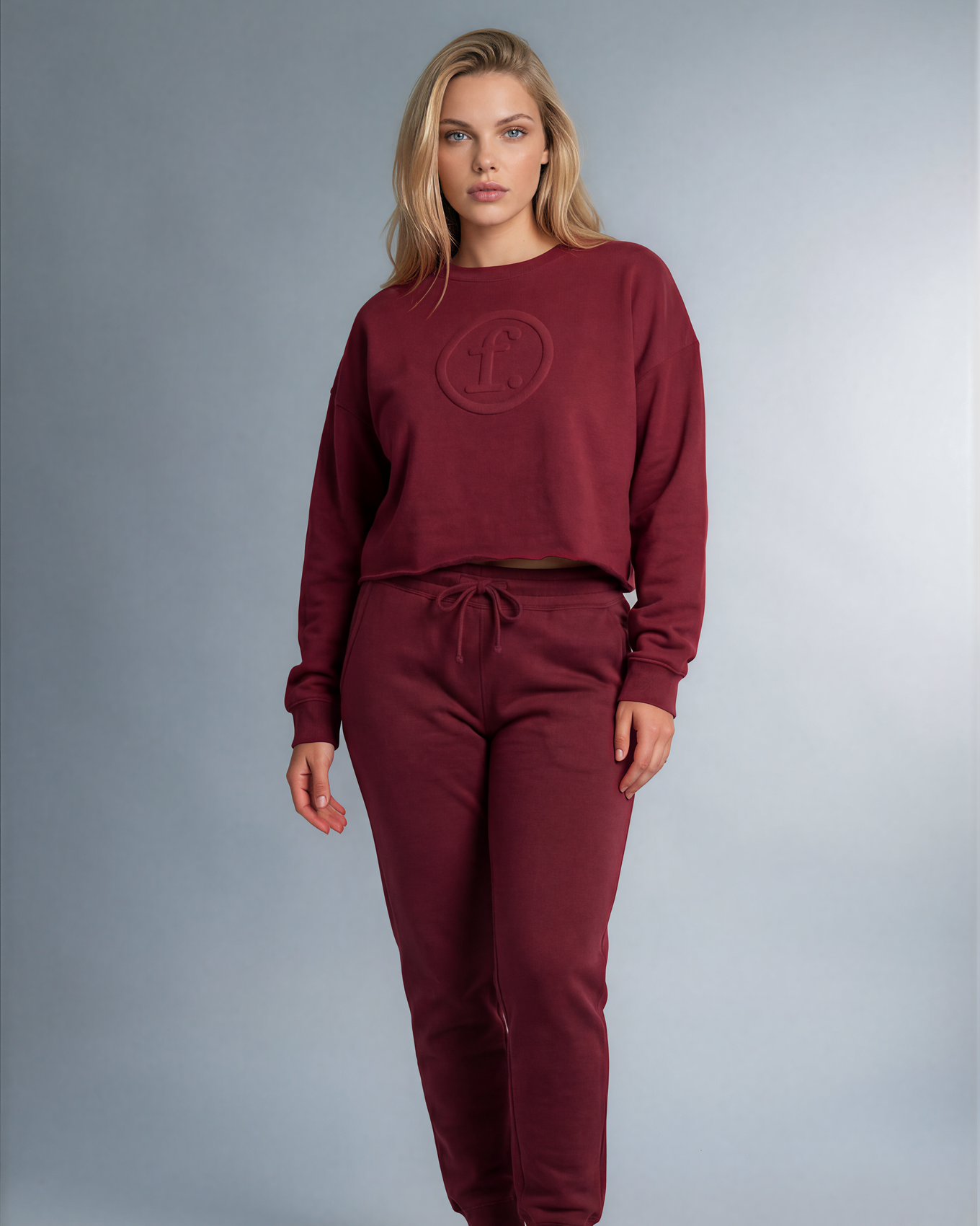 Woman wearing a burgundy sweatshirt and pants set on a gray background
