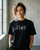 Person wearing a black t-shirt with text in a minimalistic setting