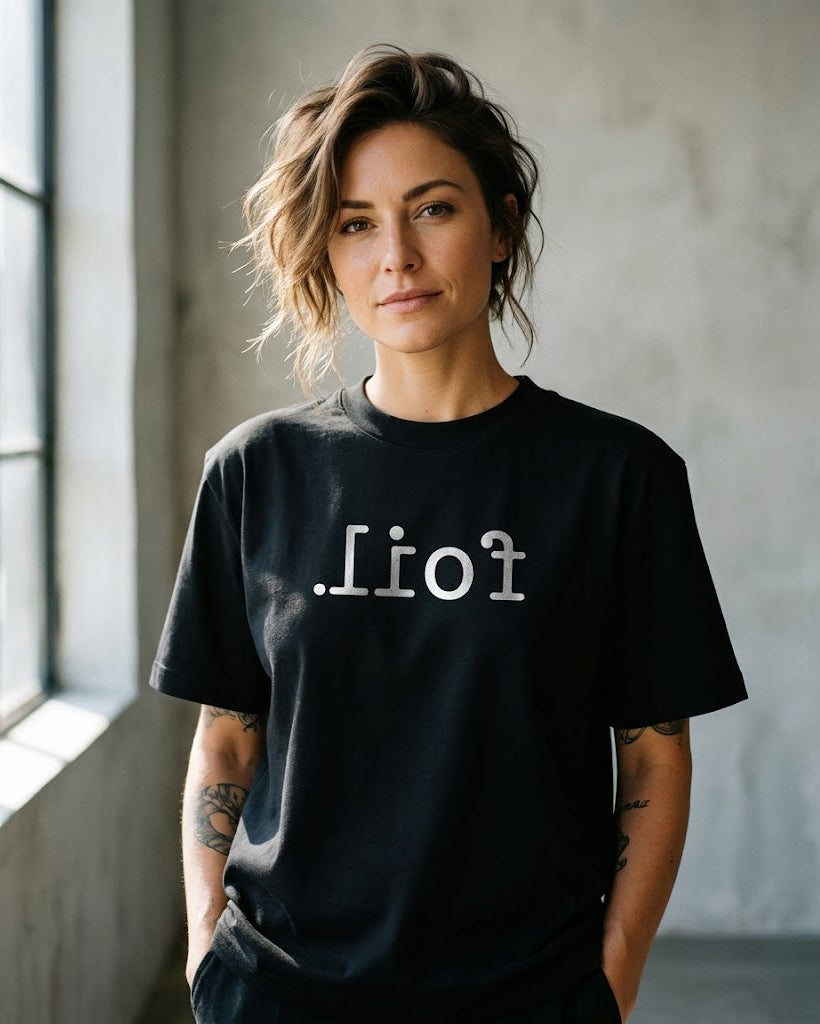 Person wearing a black t-shirt with text in a minimalistic setting