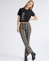 Woman wearing a black t-shirt with 'foil' text and plaid pants on a white background