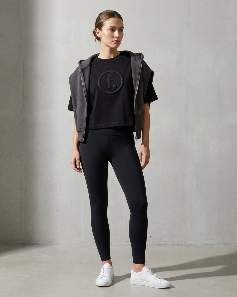 Woman wearing a black outfit with a logo on a gray background