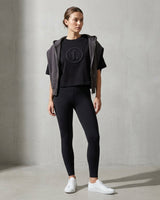 Woman wearing a black outfit with a logo on a gray background