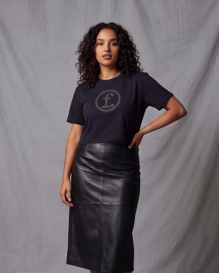 Woman wearing a black t-shirt with a logo and a black leather skirt against a gray background
