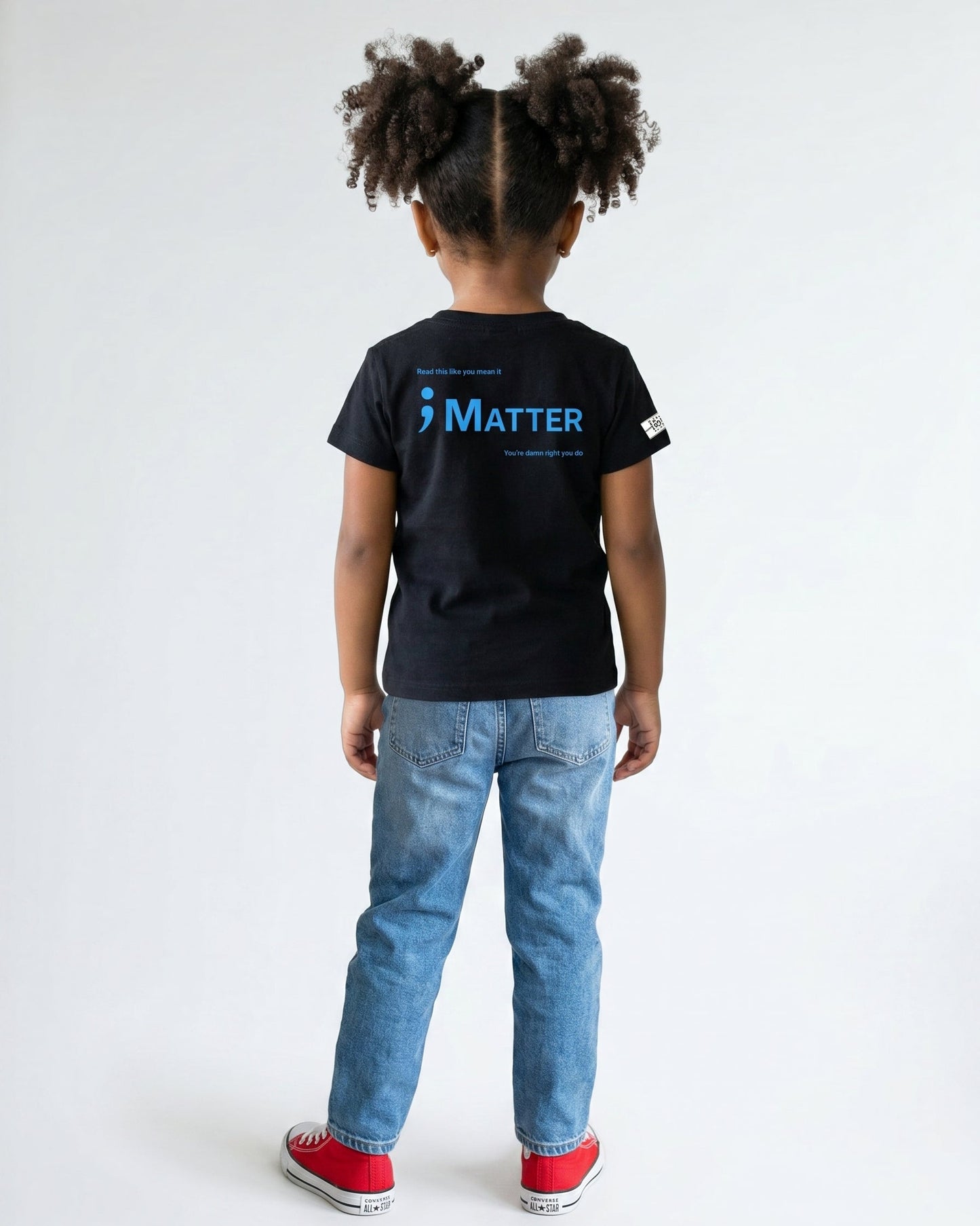 Child wearing a black t-shirt with ';Matter' logo on the back, standing against a white background